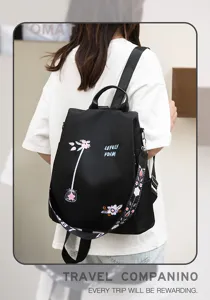 Detailed back view of black oxford backpack with floral embroidery worn by a model