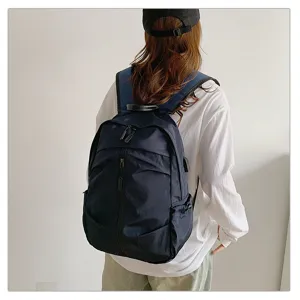 Vista trasera de una mochila casual azul marino llevata por una modelo moderna.