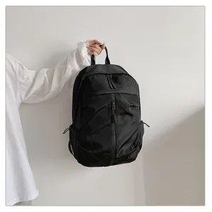 Vista detallada de una mochila casual negra de gran capacidad sostenida con la mano