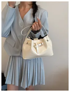 Elegante crèmekleurige bucketbag in Franse retrostijl met metalen gesp op het model