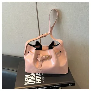 Detailopname van een roze Franse vintage emmer tas met elegante gesp op een zwart boek decor.