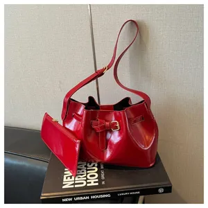 Detailopname van een rode retro bucket bag met gesp op een decoratief boek geplaatst