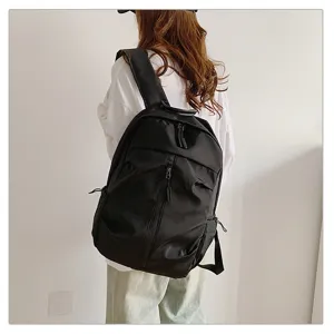 Vista trasera de una mochila negra minimalista de gran capacidad llevada por una persona de blanco