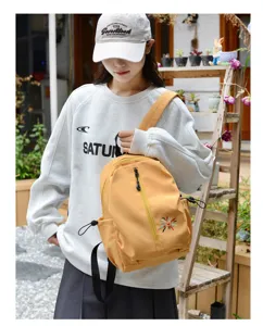 Scatto lifestyle di una donna con un piccolo zaino giallo leggero in un giardino
