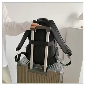 Detalle de mochila negra con banda para trolley sobre maleta plateada