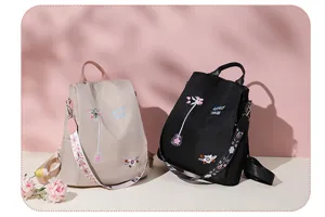 Detail shot of black and beige oxford backpacks with exquisite floral embroidery