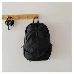 Vista detallada de una mochila negra colgada en un gancho de madera con auriculares