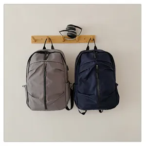 Mochilas minimalistas de nailon gris y azul marino colgadas en un perchero de madera limpia