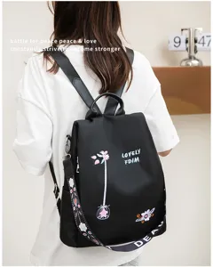 Detail of black Oxford backpack featuring floral embroidery and patterned shoulder strap