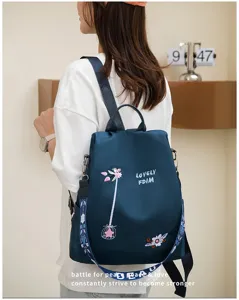 Close-up of blue oxford backpack with floral embroidery worn by a model