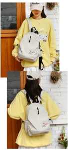 La modella indossa un piccolo zaino beige leggero decorato con ricami colorati