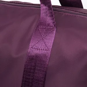 Macro detail showing durable reinforced cross-stitching on a purple nylon travel bag strap