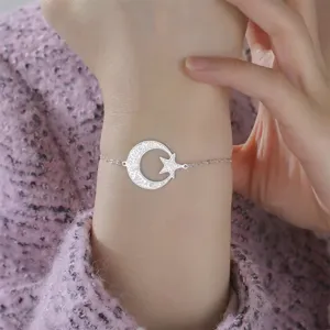 Detalle de una pulsera de acero plateada con luna y estrella y caligrafía árabe