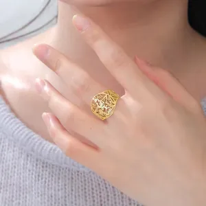 Detaillierte Nahaufnahme eines goldfarbenen Edelstahlrings mit Pentagramm-Ausschnitt am Finger.