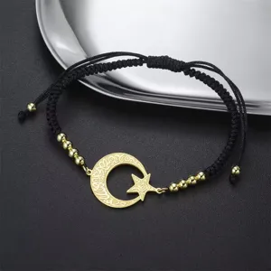 Detalle de colgante luna estrella oro en pulsera cuerda trenzada negra con cuentas acero