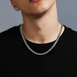 Detail view of a men's stainless steel Cuban chain necklace worn over a black t-shirt