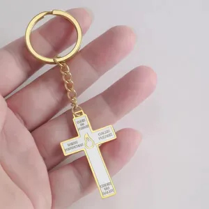 Close-up detail of a stainless steel cross keyring with white enamel and French text