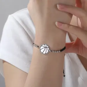 Primo piano di un braccialetto minimalista in acciaio inossidabile con ciondolo basket al polso