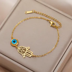 Close-up of gold stainless steel Hamsa and Evil Eye bracelet on a beige jewelry box