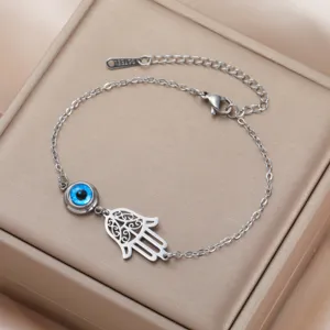 Close-up of silver Hamsa Hand and blue Evil Eye charms on stainless steel bracelet
