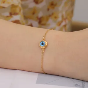 Close-up of a blue evil eye charm bracelet in gold-plated stainless steel on a wrist