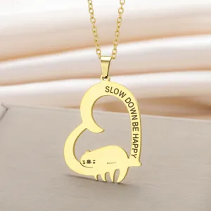 Detailopname van gouden hartvormige hanger met luiaard en "Slow Down Be Happy"-tekst
