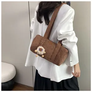 Sac bandoulière cylindrique en velours côtelé marron porté par un modèle