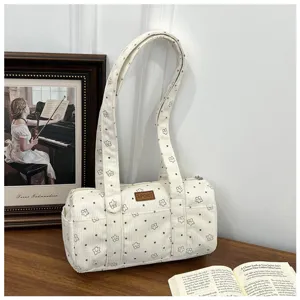 Détail d'un sac cylindrique en velours blanc avec motifs étoiles et pois sur table
