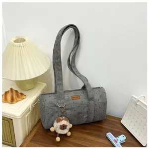 Sac à bandoulière cylindrique en velours côtelé gris avec motif d'étoiles sur un bureau