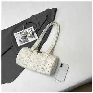 Gros plan d'un sac à main cylindrique en velours côtelé blanc à motifs étoiles noires.