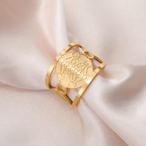Detailweergave van gouden roestvrijstalen ring met Metatron-kubus op zijde stof.