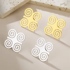 Macro view of gold and silver Adinkra symbol earrings with intricate spiral patterns