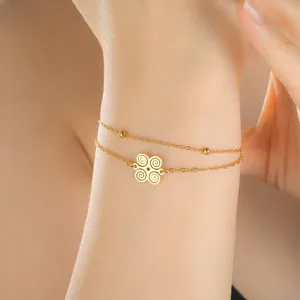 Close-up of gold stainless steel bracelet featuring a double chain and African spiral symbol.