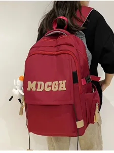 Vue arrière d'un grand sac à dos rouge avec lettrage MDCGH porté par un étudiant