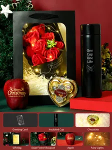 Christmas gift set with rose soap bouquet, thermos cup, chocolate, and apple for holiday.