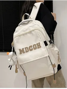 Détail d'un sac à dos blanc crème avec broderie MDCGH et breloque canard de dos