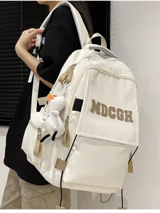 Détail d'un sac à dos blanc de grande capacité avec broderie MDCGH et breloque canard en peluche.