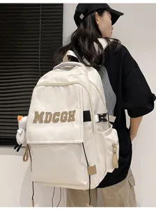 Vue détaillée d'un grand sac à dos scolaire blanc cassé avec des écussons de lettres pour