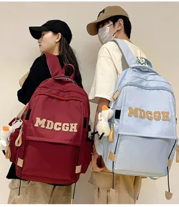 Gros plan de sacs à dos bordeaux et bleu clair élégants portés par des mannequins stylés