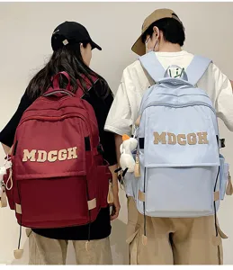 Détail de grands sacs à dos de banlieue bordeaux et bleu clair avec le logo MDCGH