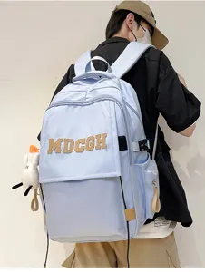 Vue arrière d'un grand sac à dos bleu clair porté par un mannequin montrant les détails