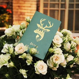 Tarjeta de Navidad con motivo de ciervo dorado entre un ramo de rosas blancas