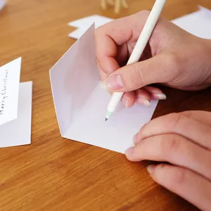 Mini biglietto d'auguri di Natale pieghevole scritto a mano su un tavolo di legno