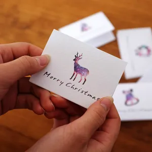 Mini biglietto di auguri di Natale pieghevole con renna stellata tenuto in mano.