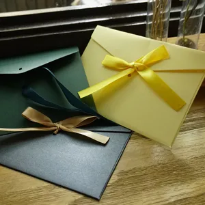 Buste eleganti in carta perlata con raffinati fiocchi di nastro su una superficie in legno