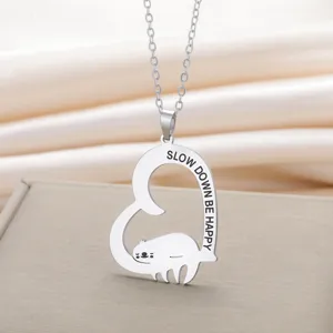 Gedetailleerde macro-opname van zilveren luiaard hart hanger met Slow Down Be Happy tekst