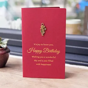 Elegant red vintage birthday card featuring gold foil greetings and a small brass girl charm
