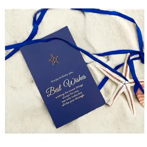 Elegante biglietto di auguri blu navy con stella in metallo dorato su fondo sabbia