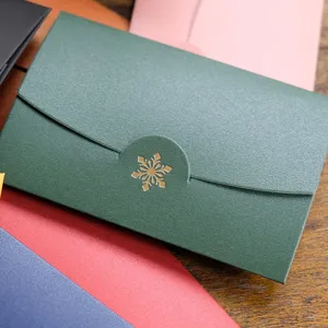 Elegante busta natalizia in carta perlata verde scuro con logo a fiocco di neve dorato.