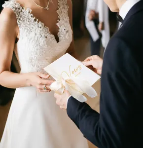 Elegant white wedding vow card with gold foil text and ribbon in ceremony